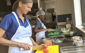 Two students wearing aprons and cutting vegetables in quantity food kitchen