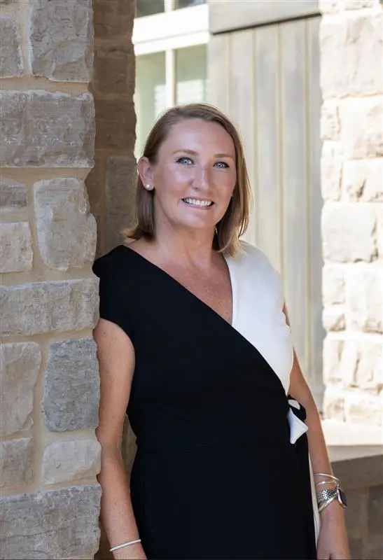 ashley elpers smiling in a formal dress next to a stone brick wall