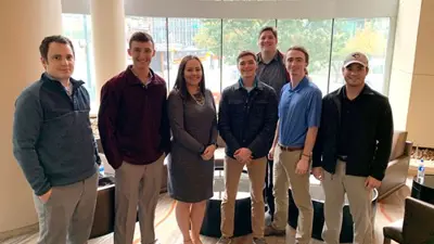 Group of USI students in business casual attire pose for a photo