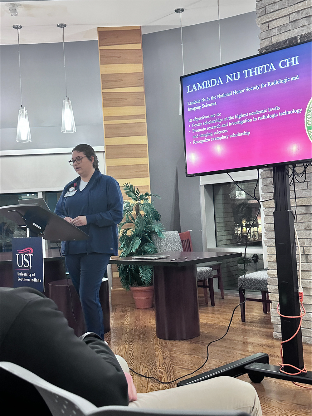 Student giving speech during Lamda Nu Honor Society Induction