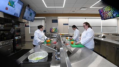 students cutting vegetables in quantity food kitchen
