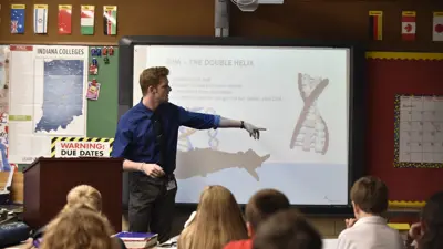 Instructor shows image of DNA double helix to a class of students