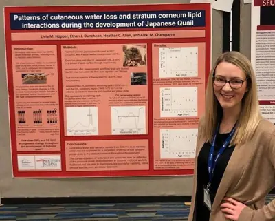 USI student Livia Hopper poses in front of her poster presentation on the development of Japanese quail at a professional conference