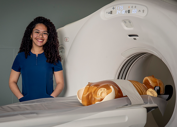 Student standing in front of CT simulator