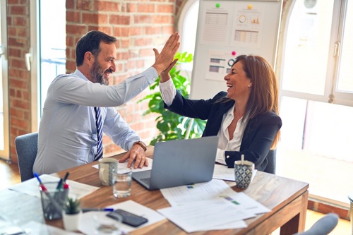 Two people high five in a professional setting
