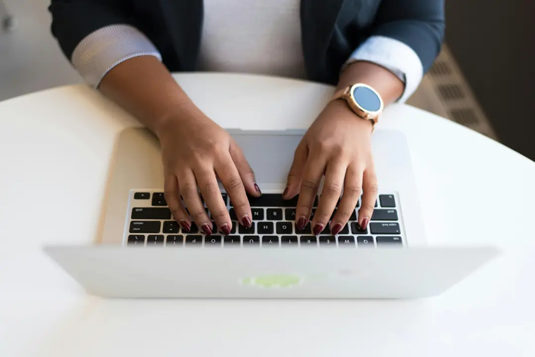 View looking down at a pair of female hands using a laptop