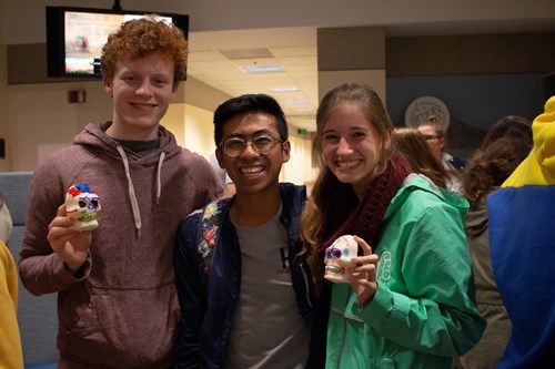 Three students pose with the Mexican sugar skulls they made at the Dia de los Muertos event