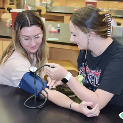 Pre-physician assistant student practicing with a blood pressure cuff on another student