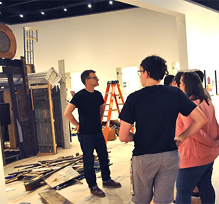 Artist in gallery speaking to people
