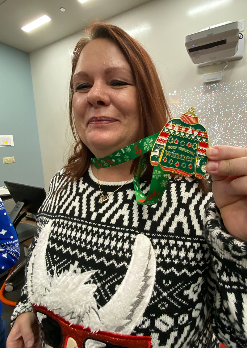Ugly sweater contest winner holding her medal
