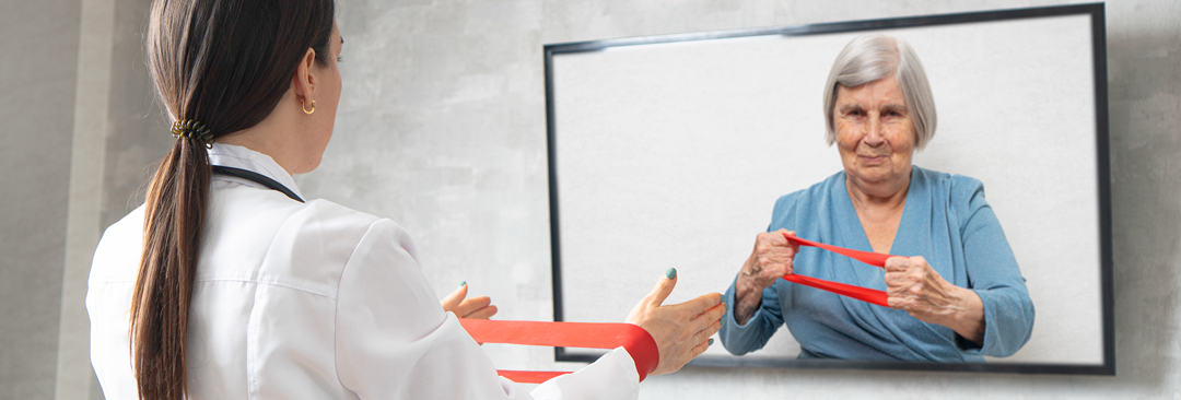 A healthcare professional demonstrating how to use a red exercise band via Telehealth to a patient displayed on a TV screen