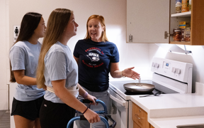 Faculty helping OT students with ADLs in simulation kitchen at Stone Center