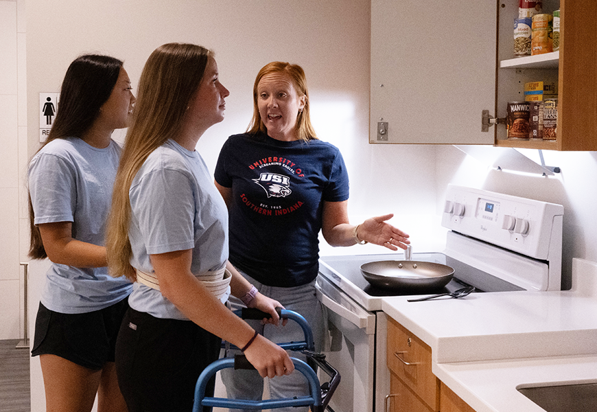 Faculty helping OT students with ADLs in simulation kitchen at Stone Center