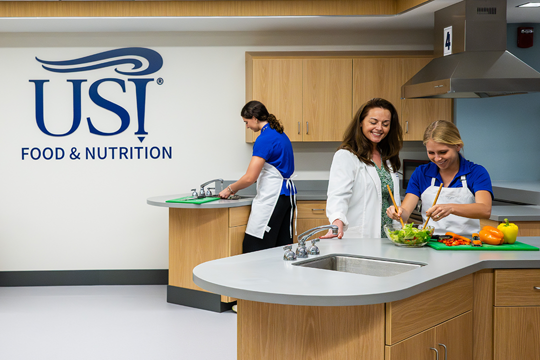 Photo of faculty with students in kitchen in lower level