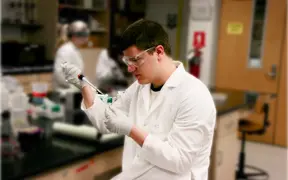 Male student uses a pipette to fill small tubes with liquid in a genetics lab