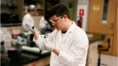 Male student uses a pipette to fill small tubes with liquid in a genetics lab