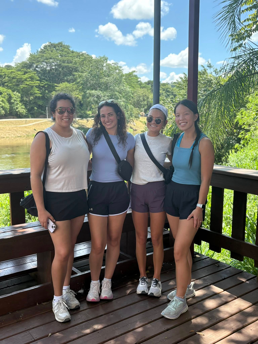 Students pose for photo on a deck with trees behind them