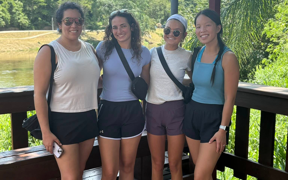 Students pose for photo on a deck with trees behind them