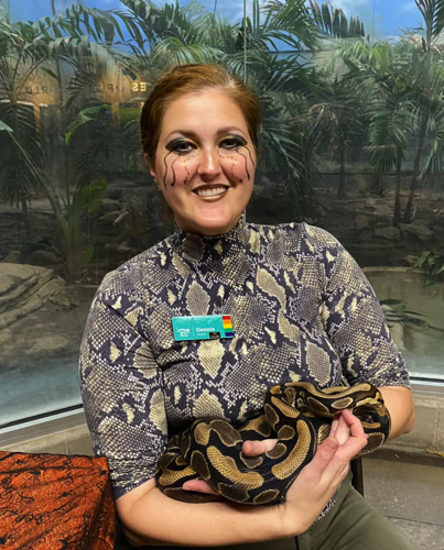 woman dressed as a snake for Halloween holding a snake