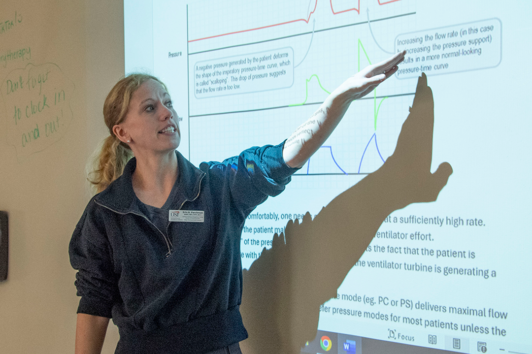 Respiratory therapy faculty member points at a powerpoint slide during a class lecture