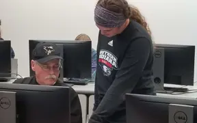 Two USI students work together in a computer lab classroom