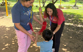 Two OT students help a child get into a swing