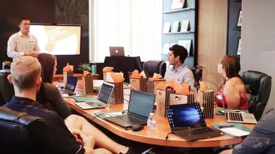 A group of people setting around a conference room table.