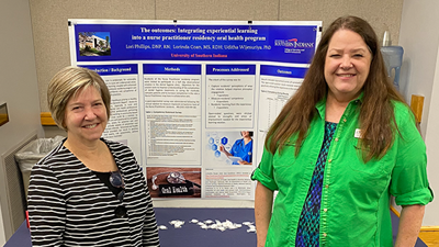 Two faculty members in front of a poster
