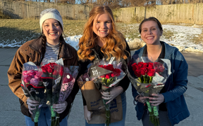 Students holding roses they are giving to nursing home residents