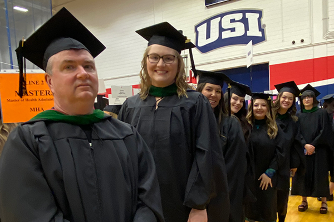 USI health administration graduates pose in their caps and gowns at commencement