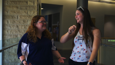 two students walking and smiling while talking