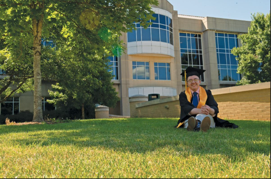 USI psychology student in cap and gown on the lawn in front of the Liberal Arts Center
