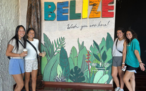 OT students in front of a sign that says "Welcome to Belize."