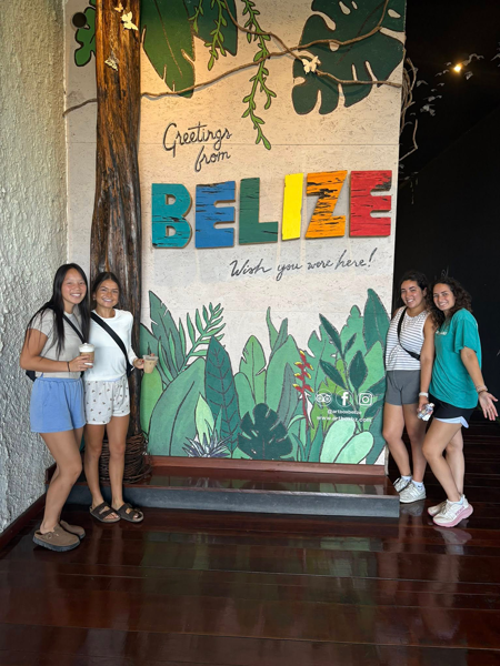 OT students in front of a sign that says "Welcome to Belize."