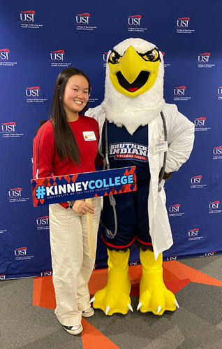 Photo of high school student standing next to Archie Eagle mascot wearing a white coat and stethescope