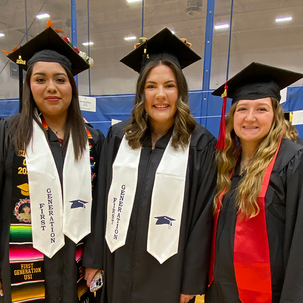 Two health administration students at graduation in caps and gowns