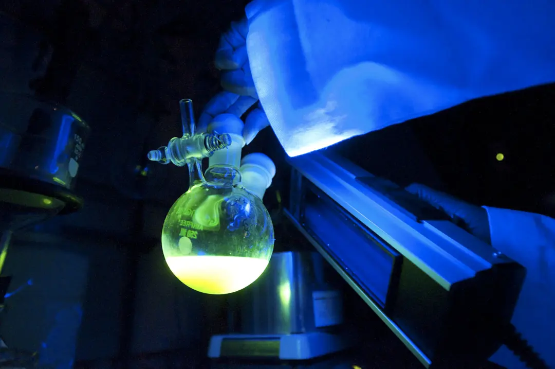 Bioluminescent substance in a flask glows under ultraviolet light in a chemistry lab