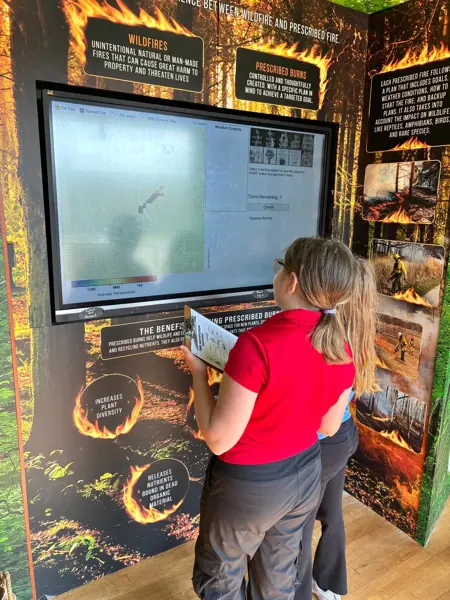 Students explore an interactive exhibit about prescribed burns and wildfire management.