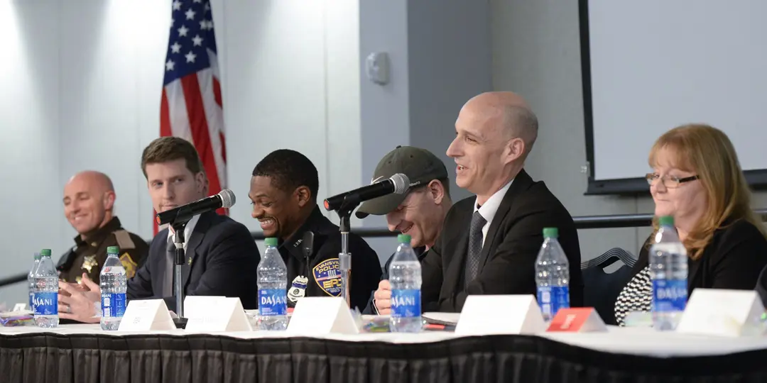 Panel of city and county law enforcement speakers seated at a table with microphones