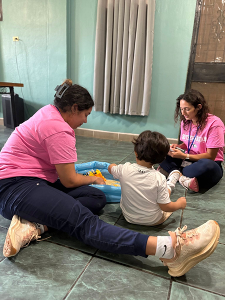 OT students sitting on the floor with a child