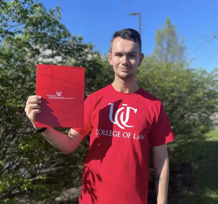 Casual portrait of USI philosophy and pre-law graduate George (Robbie) Belt '24 with his law school acceptance letter