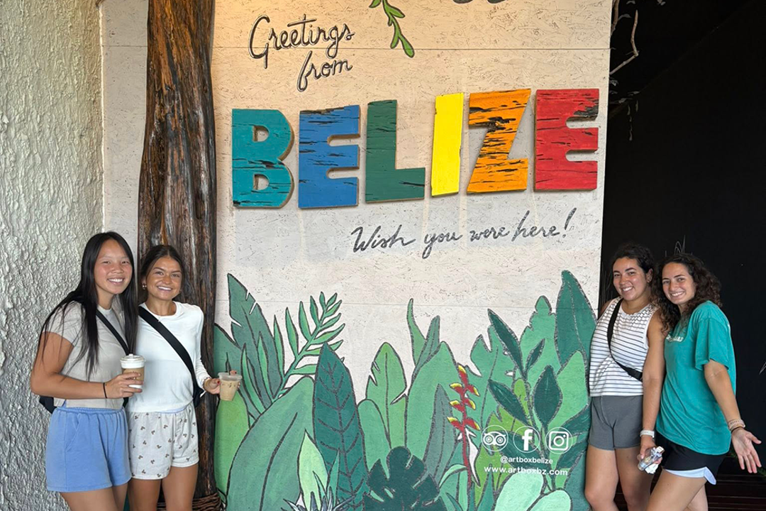 OT students standing in front of a sign that says "Greetings from Belize"