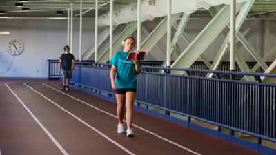 female student reading a book while exercising