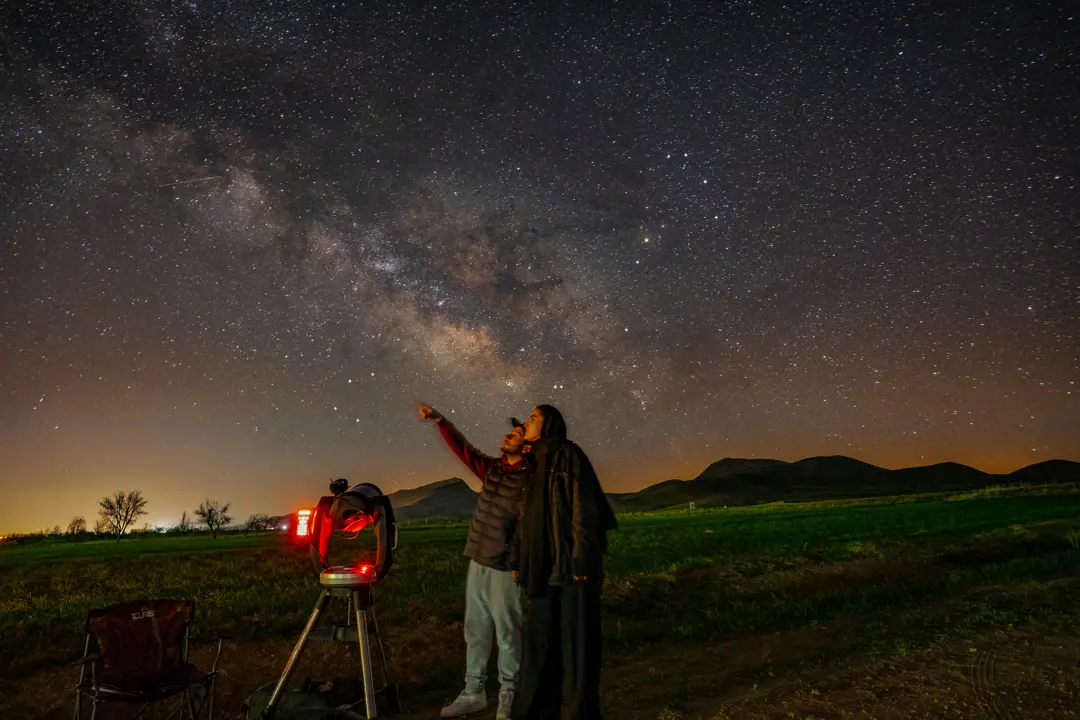 Two students in an astronomy class point at the starry night sky