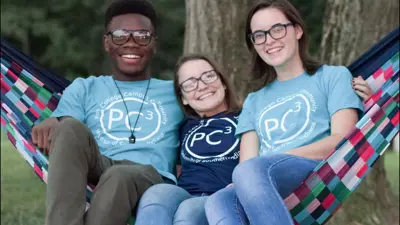 Students sit in a hammock wearing t-shirt that say "Pott College Campus Community"