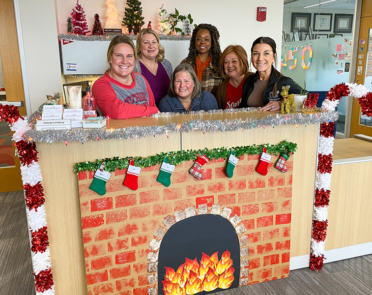 employees stand behind a desk decorated for the holidays