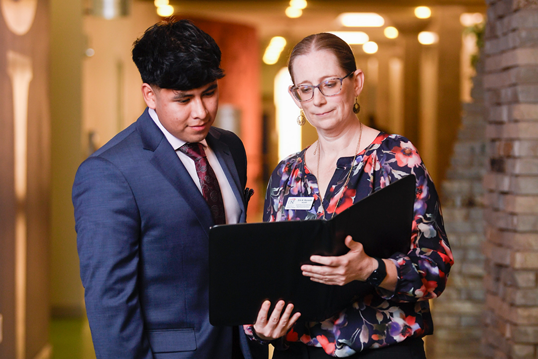 Student and faculty looking at a handbook