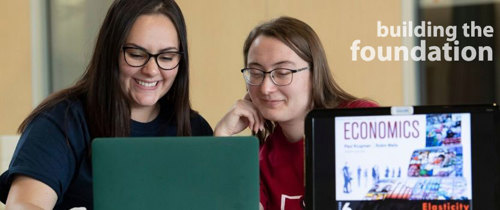 an Economics faculty member and student work together on a project. the words 'building the foundation' are overlaid