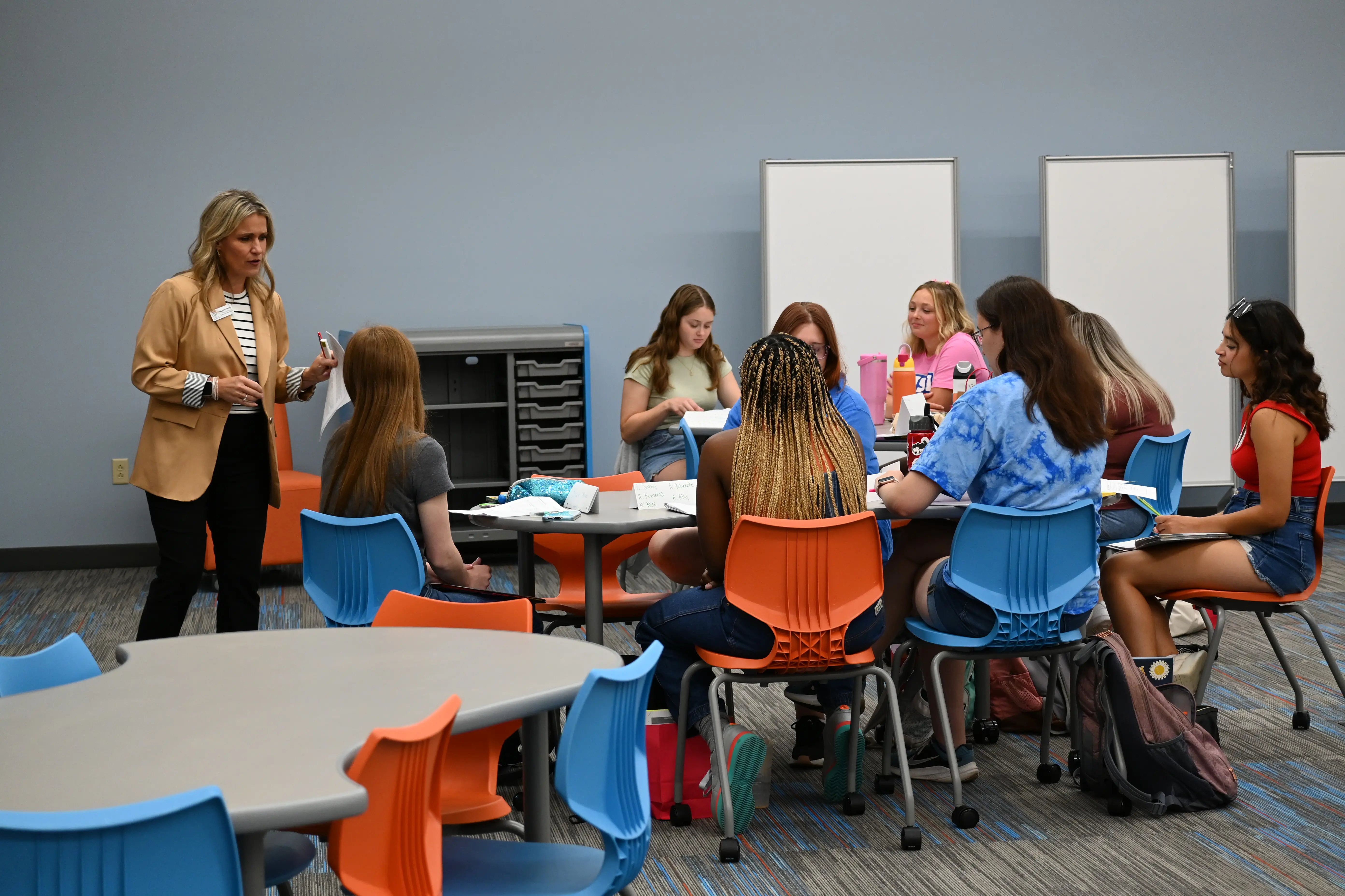 Teacher education faculty member instructs students as they sit around a table together