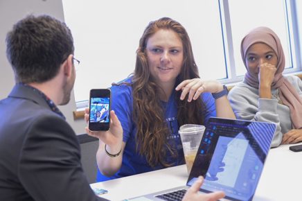 Psychology student shows her phone screen to a faculty member during class discussion